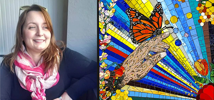 artist Dawn Kopp next to one of her color stained glass artworks showing a hand with a butterfly sitting on the fingers