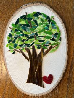 Stained glass artwork showing a tree with lots of leaves, mounted to a rounded piece of wood, by Robin Bosch