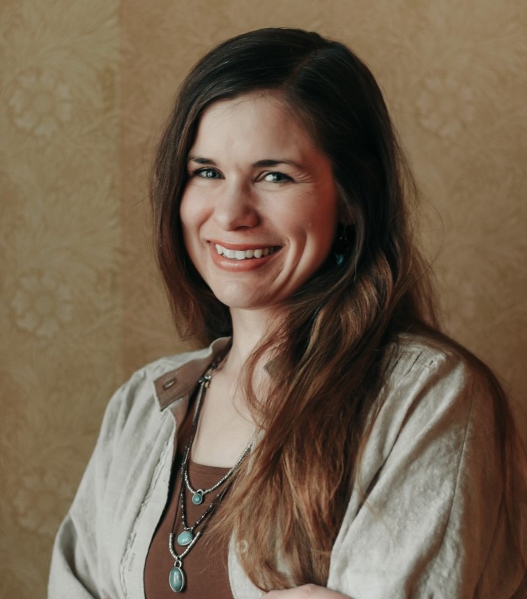 Waste-up image of caucasian Lindsey Ostlie with long dark hair, green/blue eyes and a big toothy smile