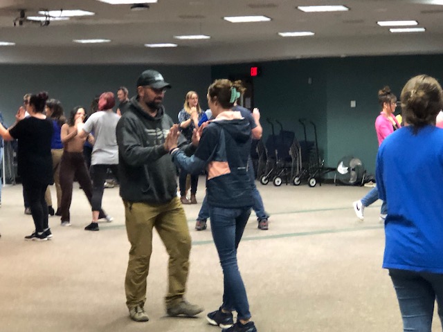 Couples in sweatshirts and jeans dance together.