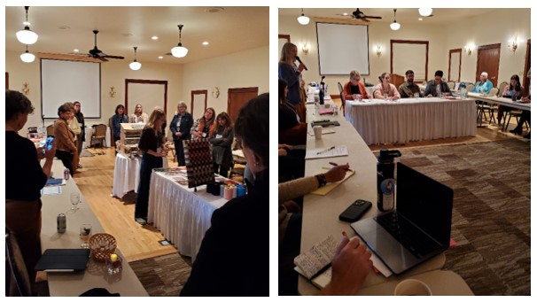 People stand near white tables; people sit at white tables and take notes.