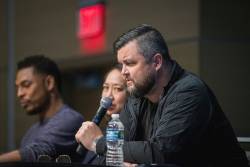 University Writers Conference showing 3 people sitting at a table, with one speaking into a microphone