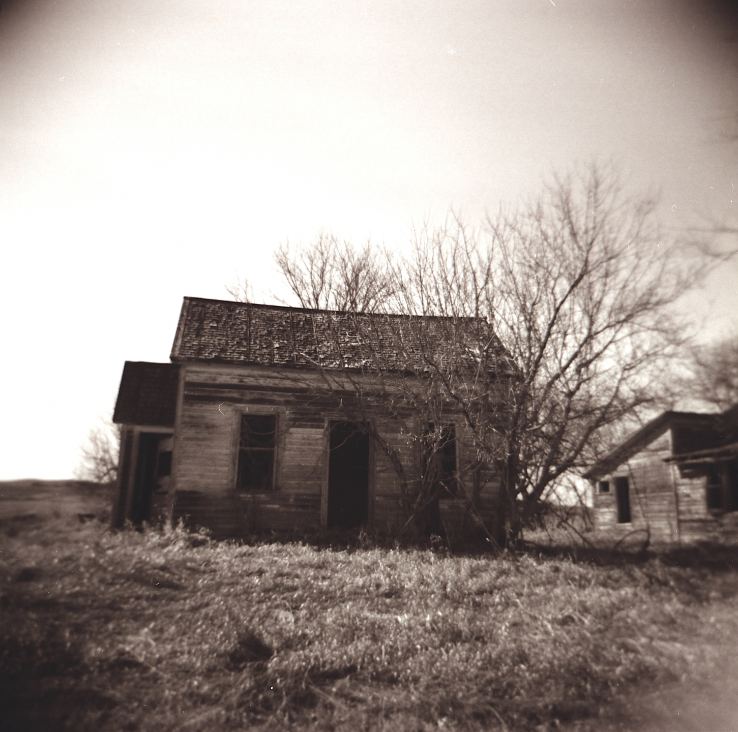 black and white photo of an old wooden farmhouse and surrounding buildings